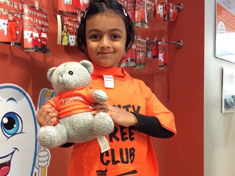 Little girl holding teddy bear cavity free club prize