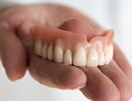 Closeup of hand holding an upper denture