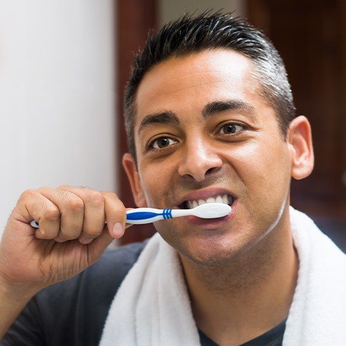 Man brushing his teeth after receiving a tooth colored filling