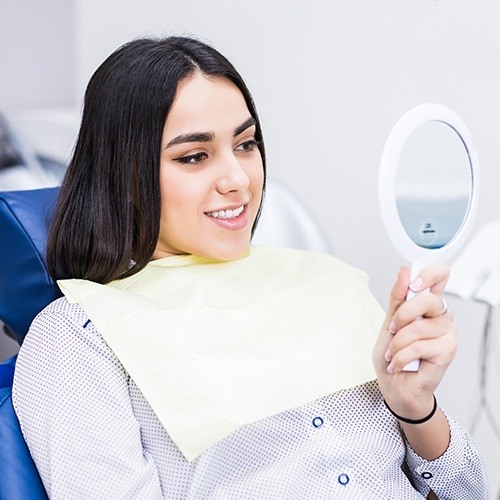 Woman looking at smile after porcelain veneer placement