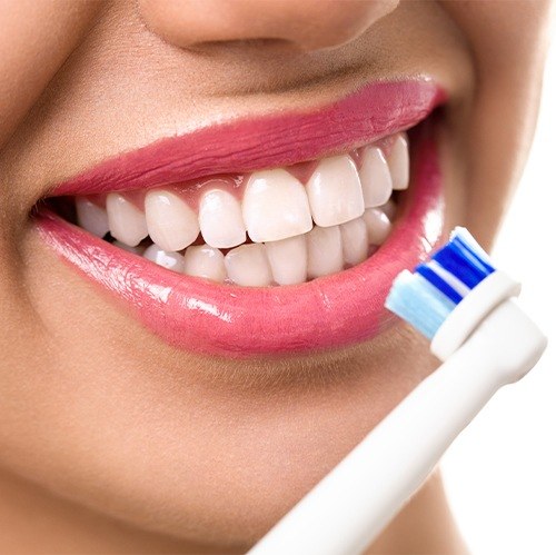 Woman brushing teeth after porcelain veneer placement