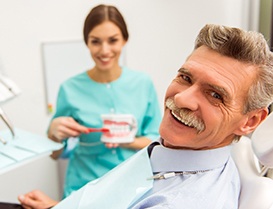 Man with mustache smiling with dental assistant in the background