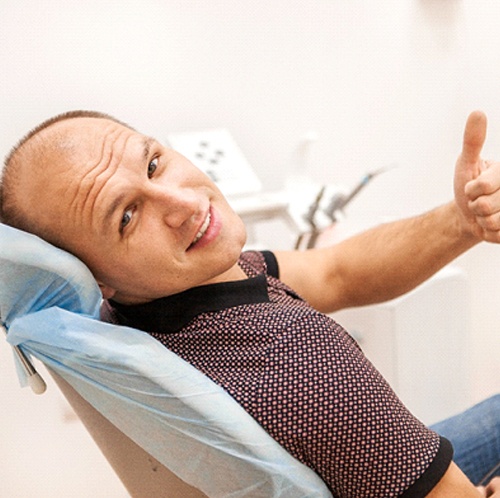 Man wearing polo giving thumbs up in dental chair