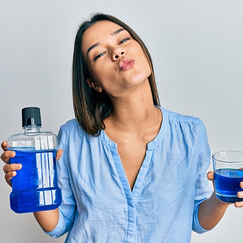 Woman holding mouthwash and swishing