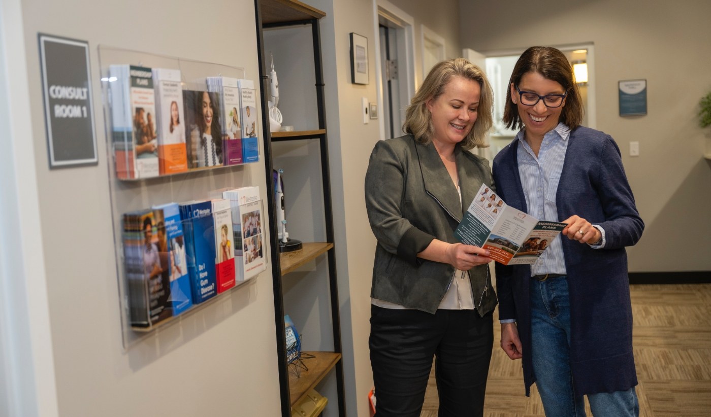Dental team member showing a patient a pamphlet for dental savings plan in Arlington Heights