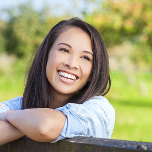Woman smiling outside with arms resting on the fence
