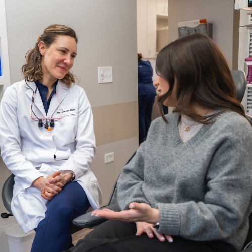 Woman in gray sweater talking to her dentist about restorative dentistry in Arlington Heights