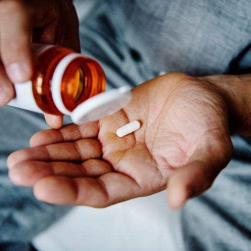 Person pouring pills from a bottle into their hand