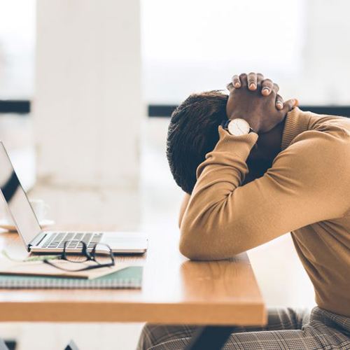Tired person stretching at their work desk