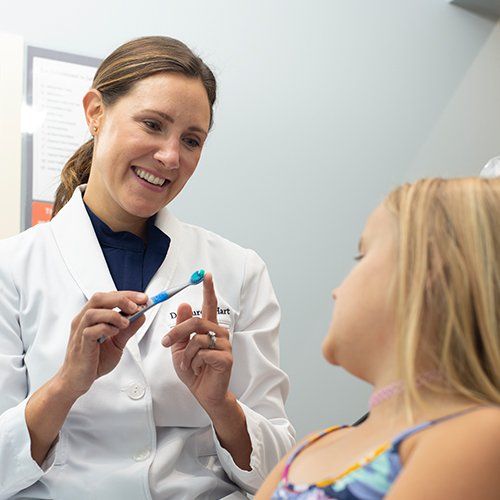 Dental team member showing child how to brush teeth