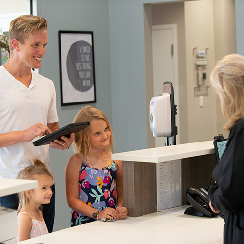Family of three checking in at dental office front desk