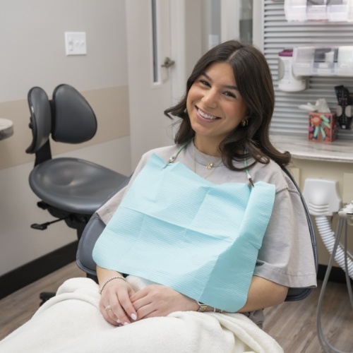 Man in collared shirt smiling while sitting in dental chair