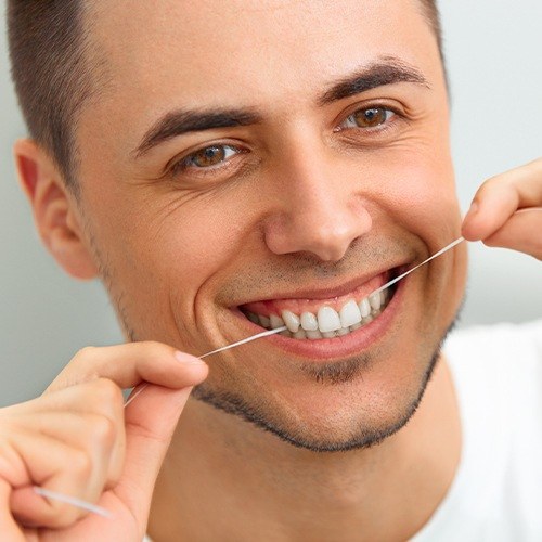 Man flossing after dental crown restoration