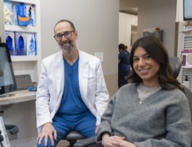 Woman in gray sweater smiling next to her dentist