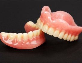 Two full dentures against black background
