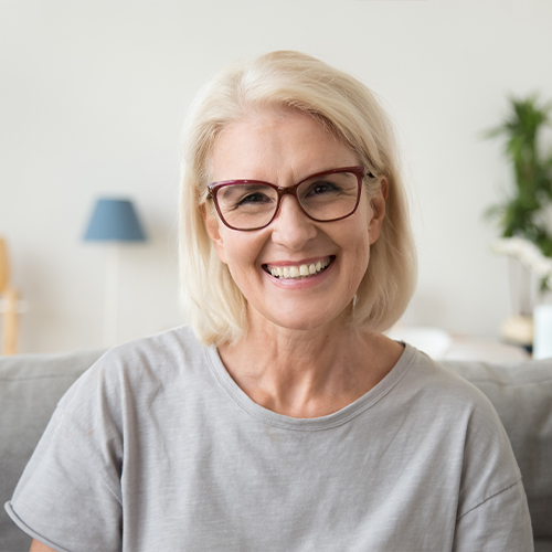 Older blonde woman smiling on couch