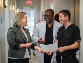 Woman talking to dentist and team member in hallway