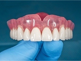 Gloved hand holding a full denture