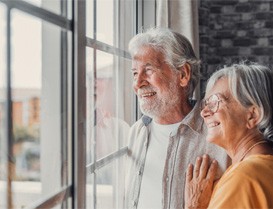 a mature couple looking out the window and smiling