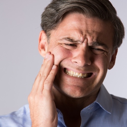 Man in need of T M J therapy holding jaw