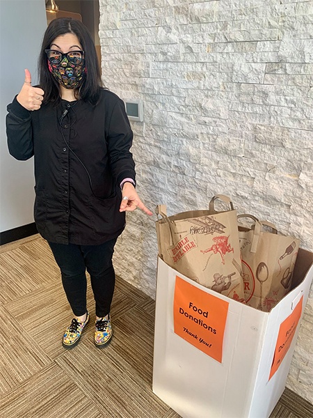 Dental team member pointing to box of food donations