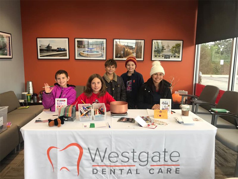Woman and several kids at indoor table labeled Westgate Dental Care