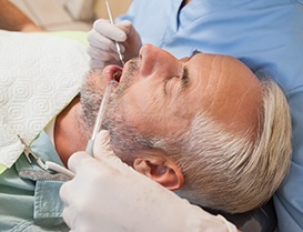 Man with greying hair laid back in dental chair with eyes closed