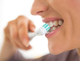 Woman with dental implants in Arlington Heights, IL brushing her teeth