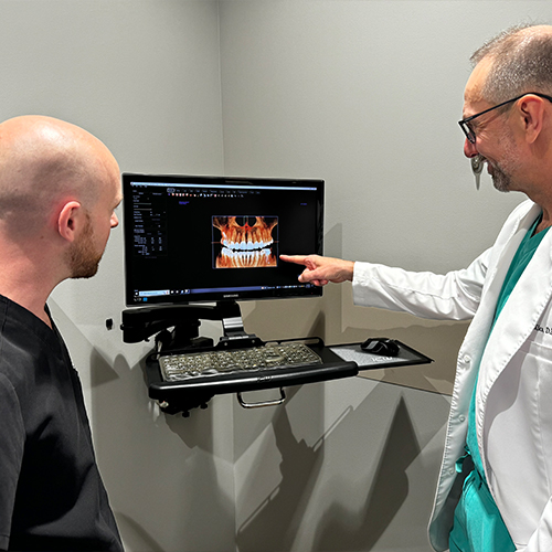 Two dentists looking at digital models of mouth with dental implants