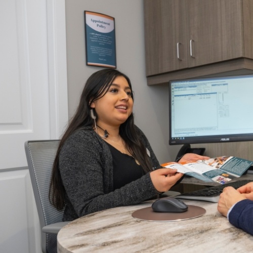 Dental team member handing a pamphlet to a patient across desk