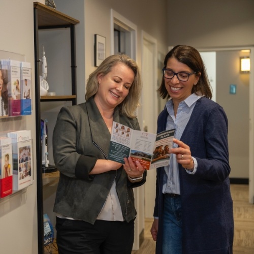 Dental team member showing a patient a pamphlet in a hallway