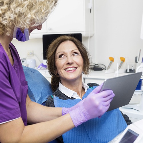 dental team member showing a patient a tablet 