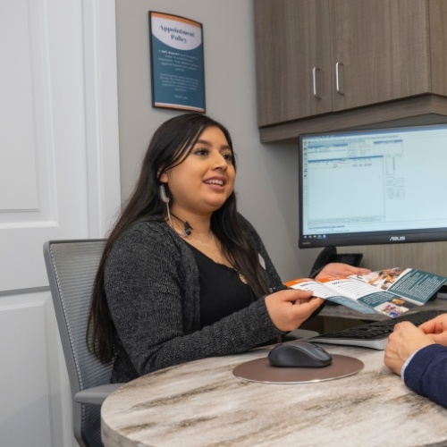 Dental team member showing a pamphlet to a patient across desk