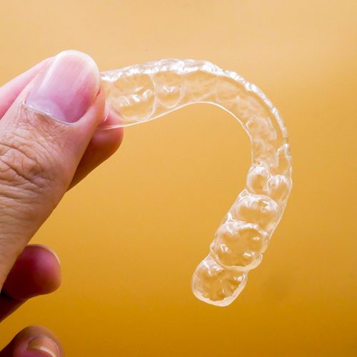 Close up of a clear aligner with yellow background