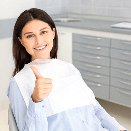Woman smiling with thumbs up in dental chair
