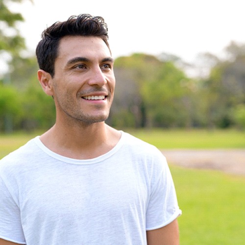 Man in white t shirt smiling while outside