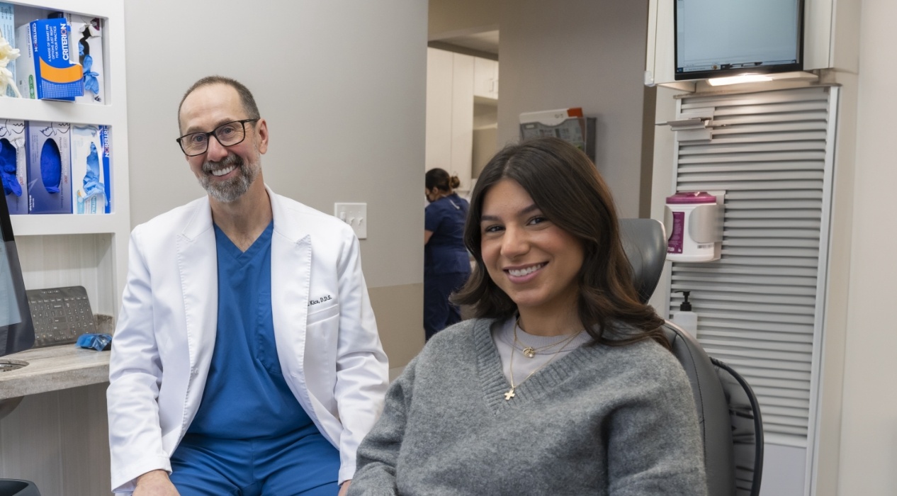 Doctor Kics smiling next to woman in dental chair