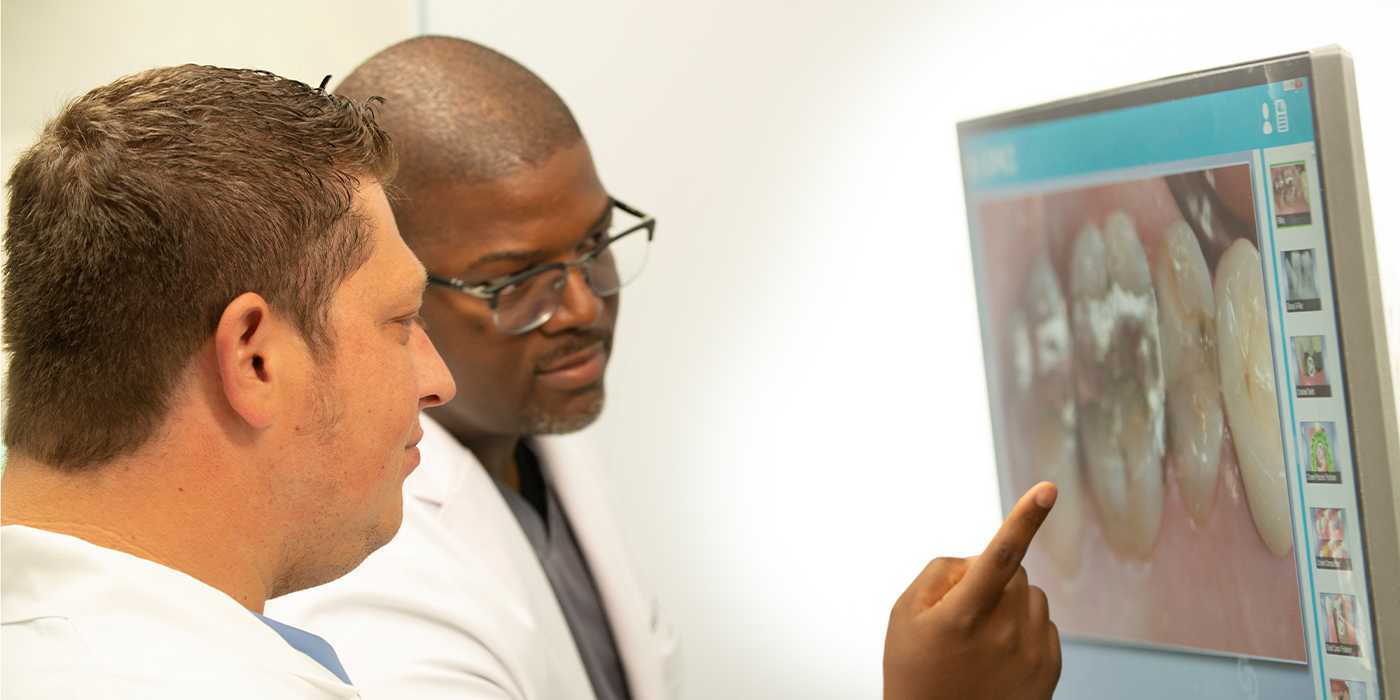 Two dentists looking at computer screen showing close up photo of teeth