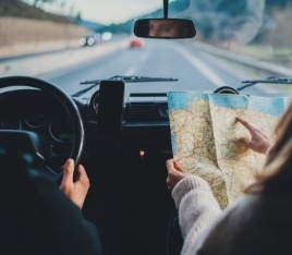 Person in passenger seat of car holding a map