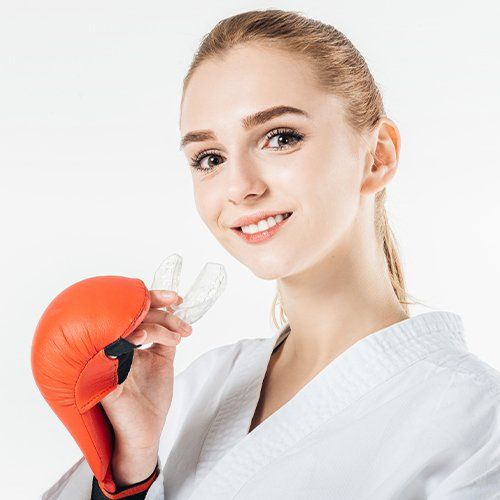 Teenage girl in boxing outfit holding a mouthguard