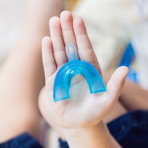 Hand holding a blue mouthguard