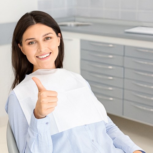 Woman smiling with thumb up in dental chair