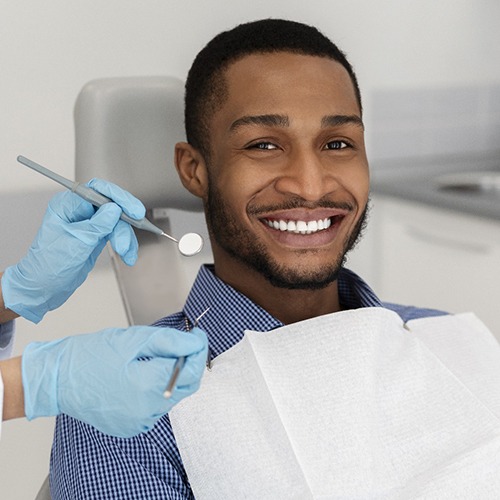 Man smiling in dental chair while wearing collared shirt