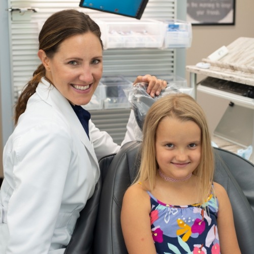 A young girl in a dentist’s chair smiling