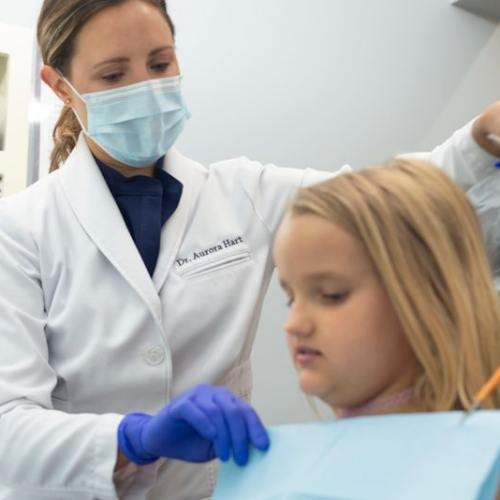 Dentist placing a dental bib around a child patient