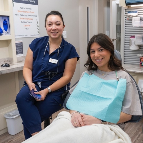 Dental team member smiling next to a patient in the treatment chair
