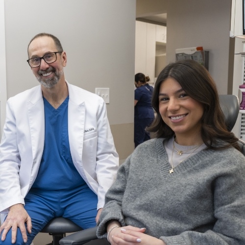 Woman in gray sweater smiling in dental chair