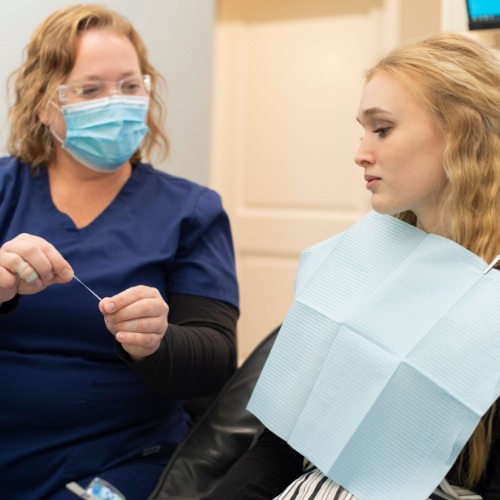 Dental team member showing floss to a patient