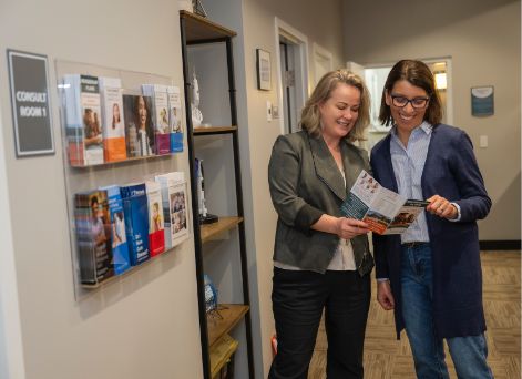 Dental team member showing a pamphlet to a patient while standing in hallway
