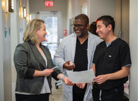 Dentist and team member with pamphlet talking to patient in hallway